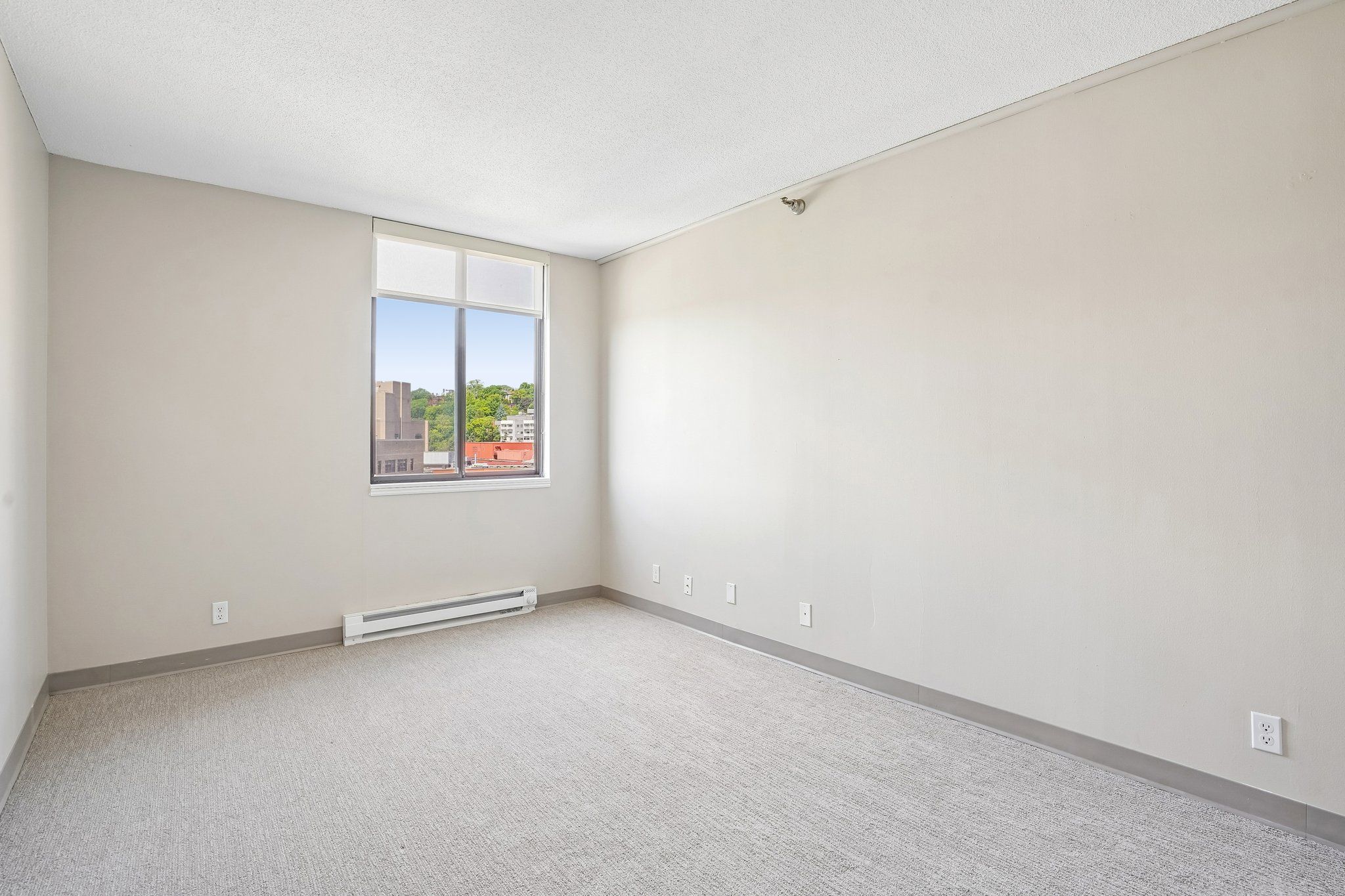 Bright Irvine Park Towers apartment bedroom with large window and carpeted flooring